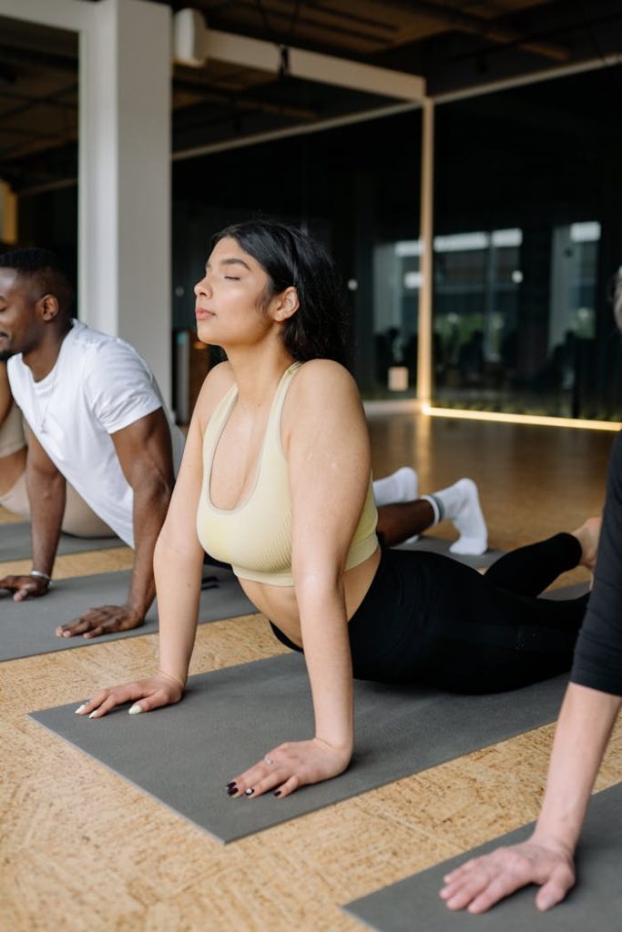 Group of adults practicing yoga cobra pose indoors for mindfulness and fitness.